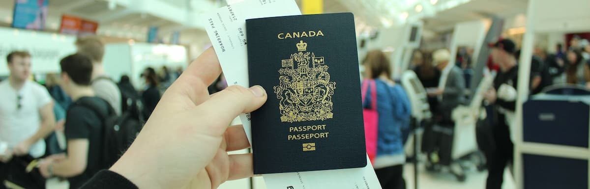 Canadian Permanent Residence. A traveler holding up a Canada passport at the airport.