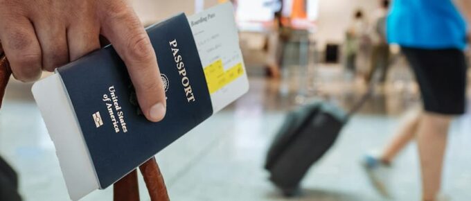 Man holding an American passport and boarding pass inside an airport terminal. Guarantee Visa Application Success