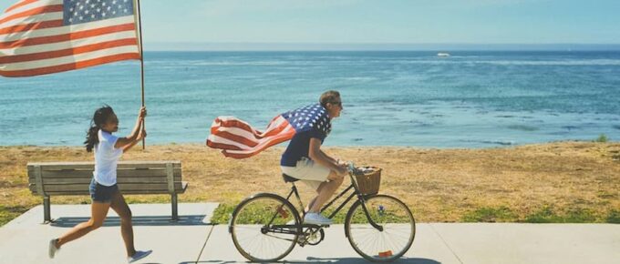 Opportunities in America. Two happy couple running draped in the American flag.