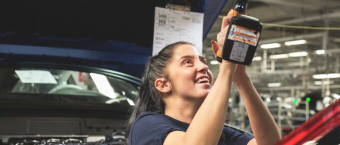 Image of a smiling female worker at a car assembly line.Paid Internship While Studying Abroad.