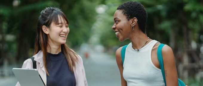 An asian female student and a Black female student share a laugh as they walk on the road. Best Student Health Insurance for Studying in Australia: 2026 OSHC Guide